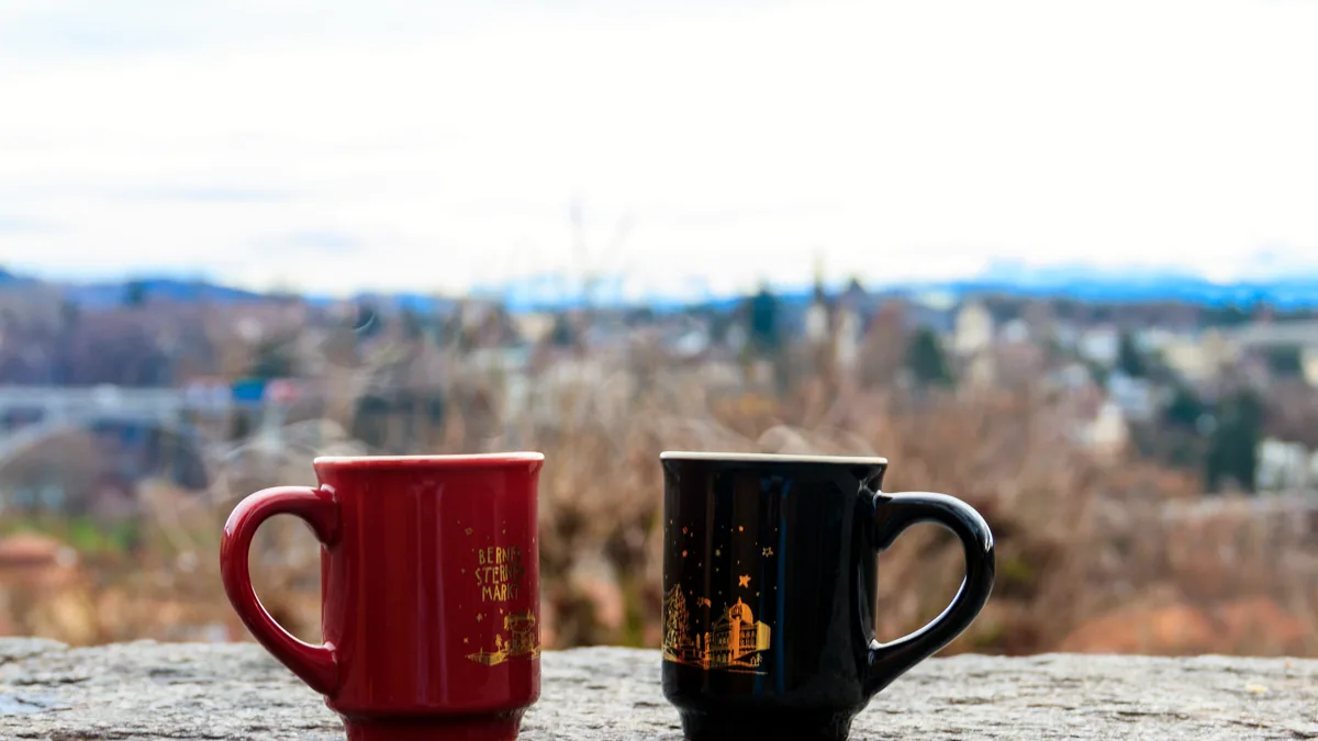 Two ceramic mugs on a stone table top with soft window light.