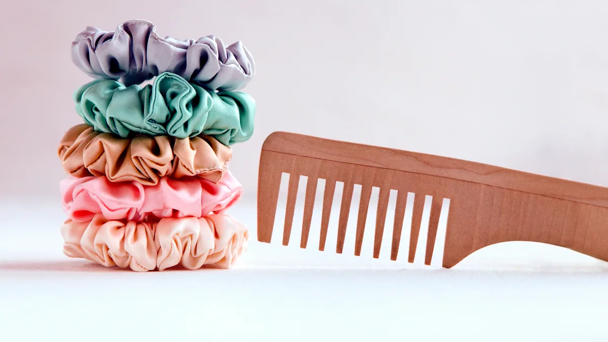 A wooden hairbrush and a fine-tooth comb on a marble bathroom counter.