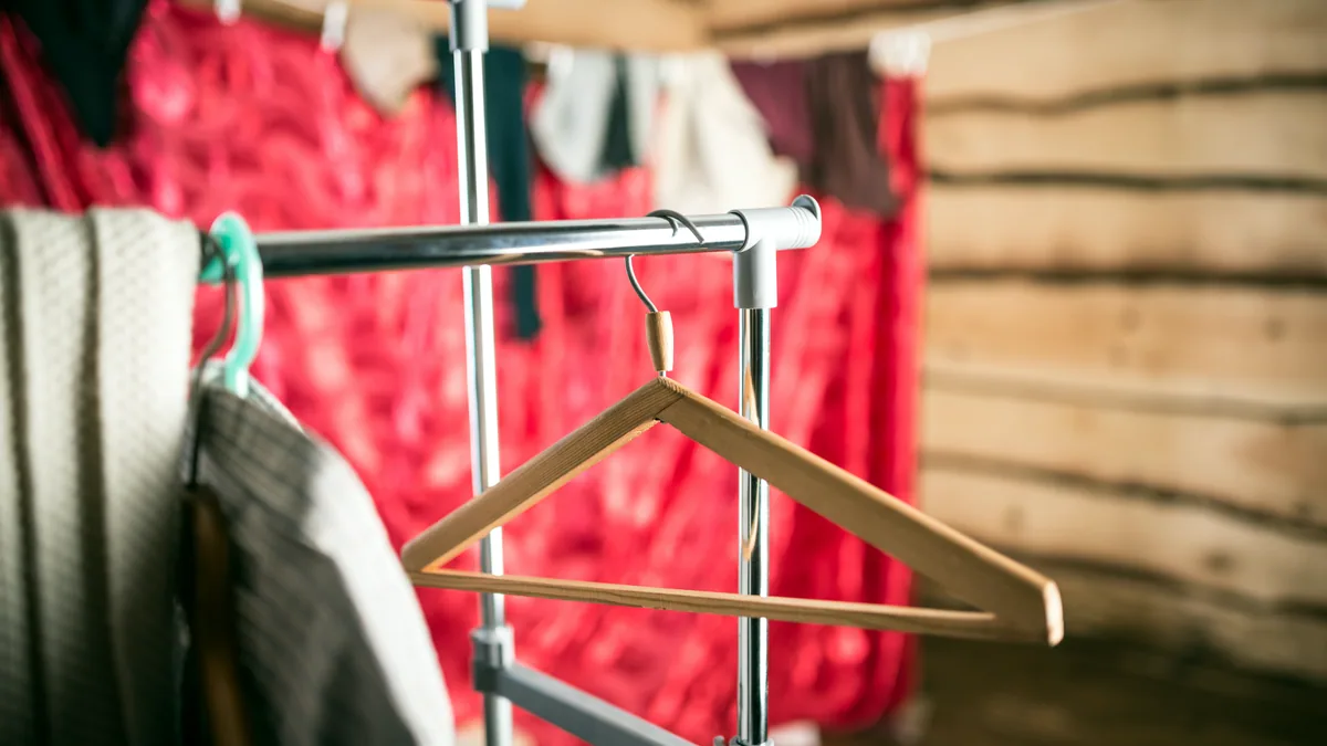 A neat rack of folded shirts on wooden hangers in warm afternoon light.